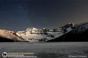 Frozen Cameron Lake in Waterton Lakes National Park at night with stars